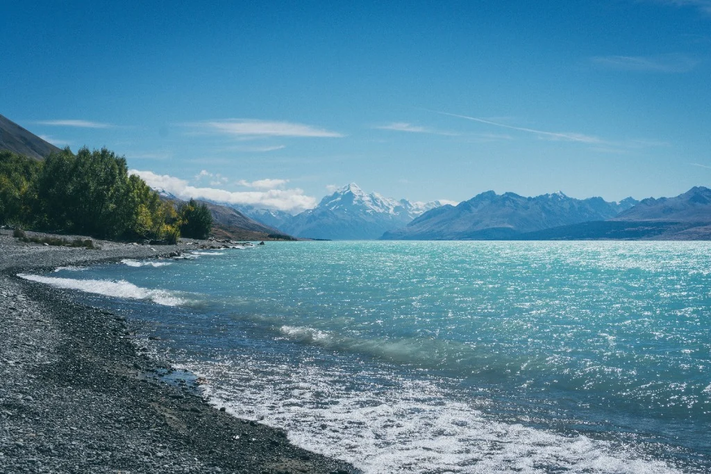 Vibrant turquoise waters of Lake Pukaki with snow-capped Mount Cook peaks